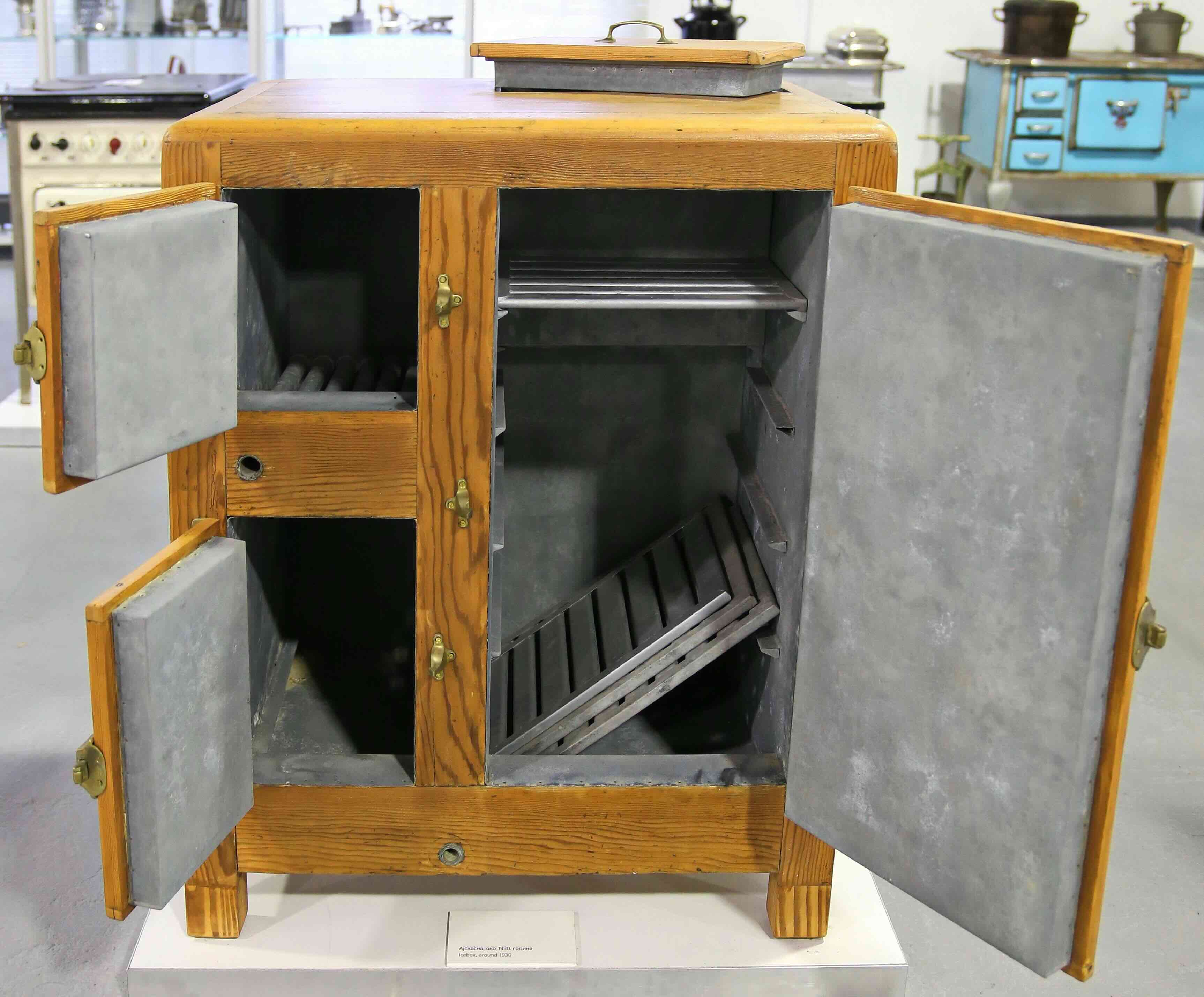 Early 20th-century icebox refrigerator with metal-lined compartments and food storage shelves.